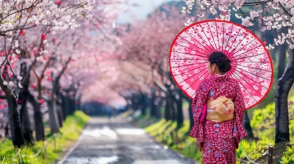 Selbstklebende Fototapeten Asian woman in a cherry blossom garden on a spring day Rows of cherry trees in Kyoto Japan © Lakkhana