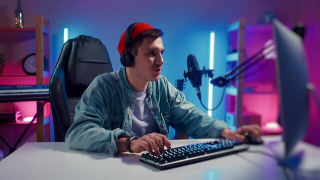 gamer guy blogging, commenting hard match, looking at computer monitor, using computer mouse and keyboard. Cybersport, gaming club. Young Handsome Pro Gamer live stream playing Online Video Game