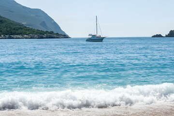 yacht in the distance on sea, wave is breaking near beach with white sand, island with mountain behind it, sunny day
