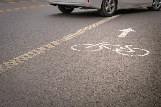 A vehicle crossing a bicycle lane marked with painted bike and directional arrow symbols.