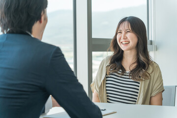 投資信託・マネー相談・個別相談を受ける若いアジア人女性とカウンセリングするビジネスマン男性
