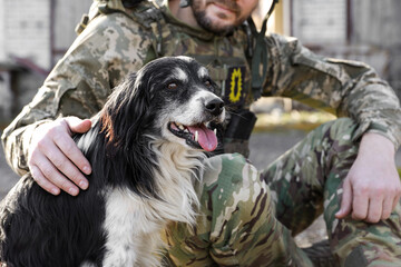 Ukrainian soldier stroking stray dog outdoors, closeup