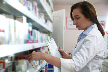 Professional pharmacist near shelves with merchandise in modern drugstore