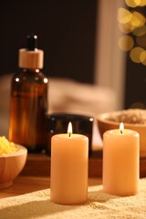 Spa composition with burning candles and personal care products on soft light surface, closeup