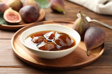 Bowl of tasty sweet jam and fresh figs on wooden table