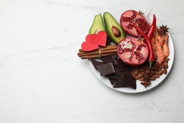Natural aphrodisiac. Different products and paper hearts on white marble table, top view. Space for...