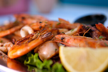 Seafood appetizer. Roasted prawns served with parsley and lemon slices. Isolated over white background 