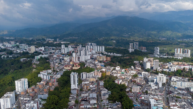 Aerial view of the city of Armenia, Quind&iacute;o, Colombia. Buildings in the city of Armenia between trees and the green mountains in the background