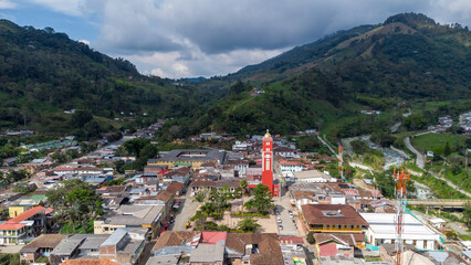 Fototapeta premium Aerial view of the green mountains and the river in the municipality of Pijao, Quindío, Colombia. Pijao, city without rush. Main park and church of Pijao.