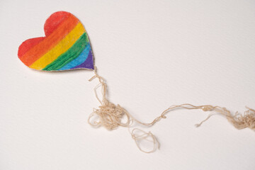 corazón de tela pintado como bandera del orgullo gay, simulando volar con hilos 