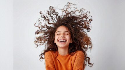 A 14 year old girl wearing braces with curly hair, laughing heartily on a plain white background
 - obrazy, fototapety, plakaty