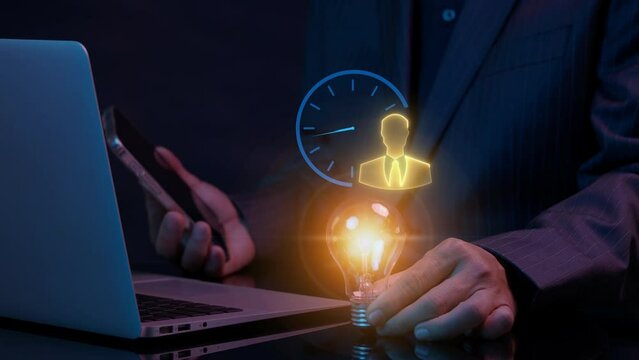 Businessman working with laptop to show glowing lightbulb and animation of businessman icon with wall clock. Startup, creative idea, innovation, technology, competition, business strategy concept.