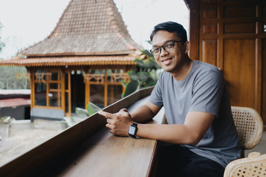 Smiling Asian man holding smartphone while sitting in a cafe restaurant