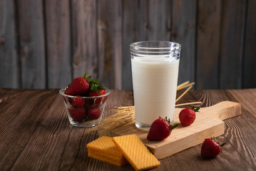Glass of milk, cookies and strawberries on wooden table, Breakfast concept.