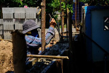 Construction workers pour concrete on cement wall new house