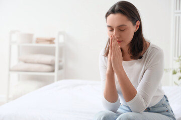 Fototapeta premium Young woman praying in bedroom