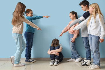 Pupils bullying little boy near blue wall