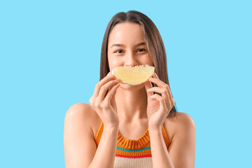 Pretty young woman with slice of ripe pomelo on blue background