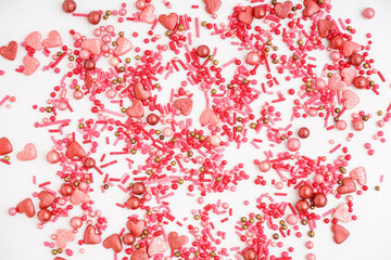 Sweet pink sprinkles scattered on white background