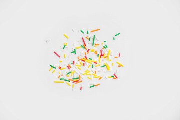 Sweet colorful sprinkles scattered on white background