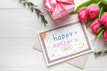 Envelope with kid drawing, gift box and tulips on white wooden background. Happy Mother's Day