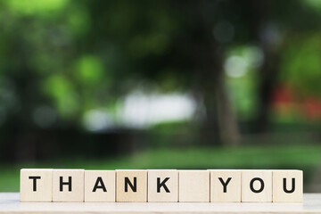 Thank you concept wooden blocks on a natural green background