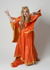 Full length portrait of plus sized woman blonde hair, wearing historical medieval fantasy gown with long flowing sleeves, golden crown of royal queen. Standing pose, isolated studio background.