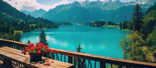 A serene view of a calm lake and towering mountains seen from a wooden deck with a table