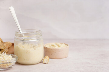 Horseradish sauce in bowls and jar with ground horseradish on white background