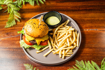 Delicious hamburger with fries in hotel restaurant on wooden table. Very tasty food. Gastronomy.