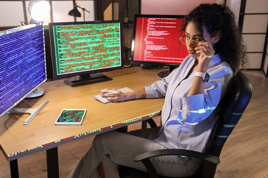 Female African-American programmer working with computer in office at night