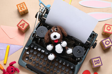 Composition with vintage typewriter, knitted toys and paper on beige background
