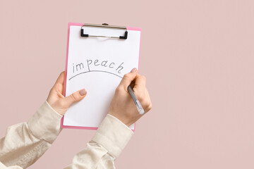 Woman holding clipboard with word IMPEACH on pink background