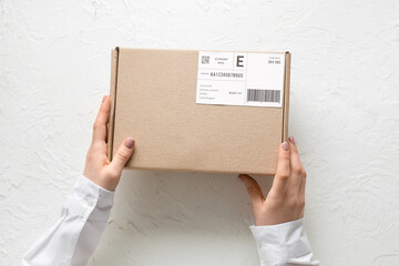 Female hands holding cardboard package with label and barcode on white background