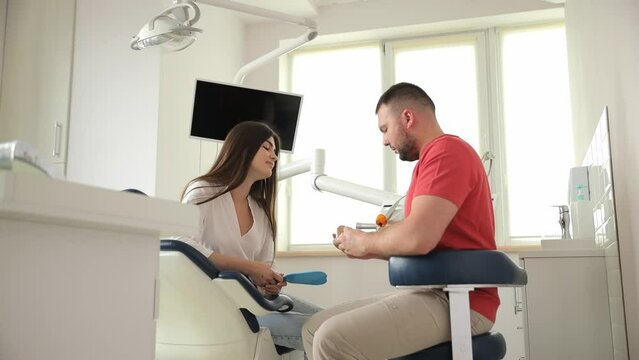 A dentist and a young long-haired patient in a modern dental office. Dentist consultation