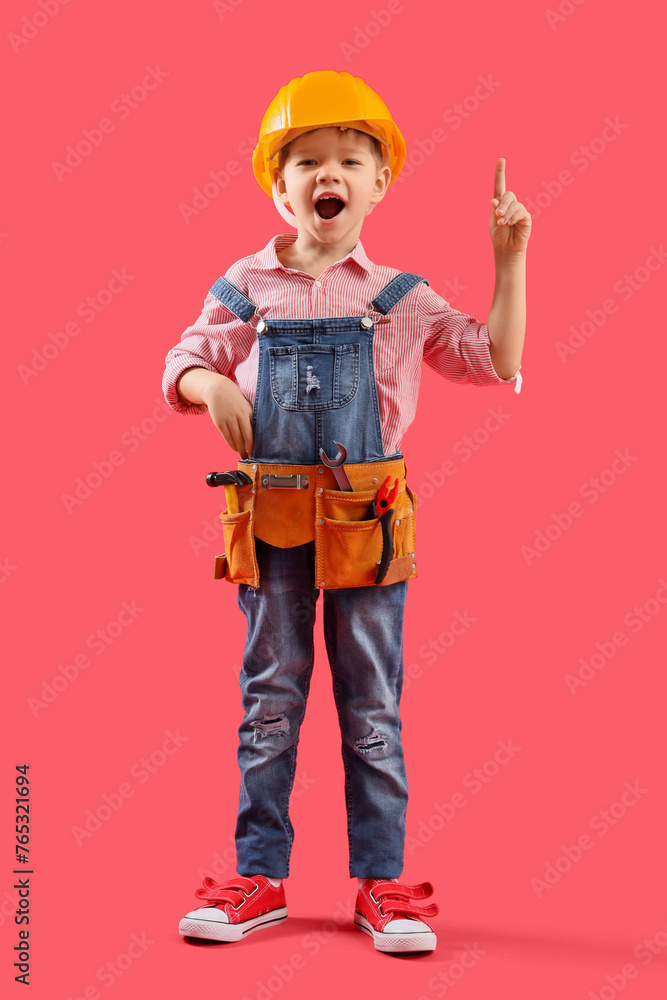 Poster cute little builder pointing at something on red background