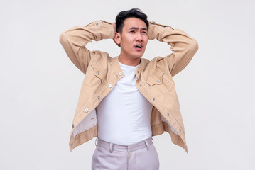 Frustrated young Asian man realizing he forgot something, hands on head against a white background