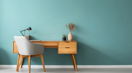 Home workplace with wooden drawer writing desk and grey fabric chair near turquoise wall with copy...