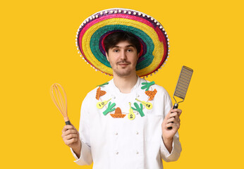 Young male chef with sombrero, whisk and grater on yellow background
