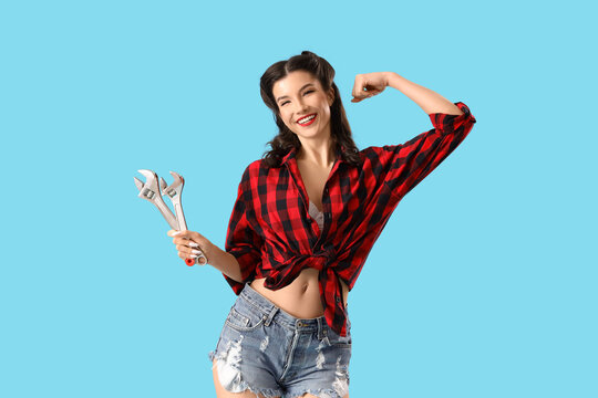Beautiful pin-up woman with wrenches on color background