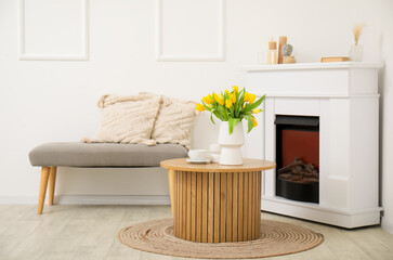 Cozy bench with cushions and vase of yellow tulips on coffee table in living room