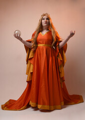 Full length portrait of plus sized woman blonde hair, wearing historical medieval fantasy gown, golden crown of royal queen. Standing pose holding crystal seer orb, isolated studio background.