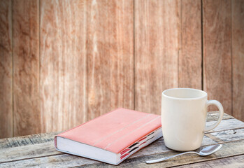Notebook and coffee cup on wood table with blurred background