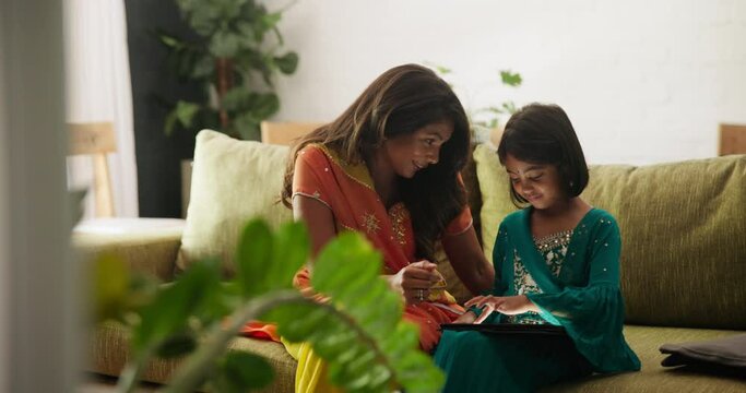 Mom, child and e learning with tablet on sofa in home living room for progress, reading and app for online course. Education, mother and daughter girl with digital touchscreen in Indian family house