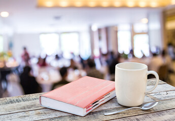 Notebook and coffee cup on wooden table with blur background