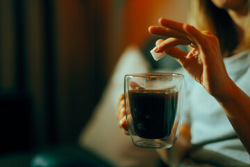 Hand Adding One Cube of Sugar in her Black Coffee. Person sweetening her drink disregarding the health risks
 - obrazy, fototapety, plakaty