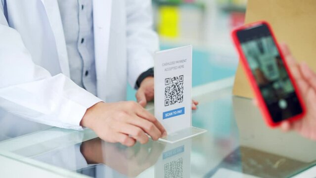 Medical pharmacy and contactless payment concept. Asian woman patient customer using mobile phone scan QR code on counter making online baking payment buying medicine and supplements in drugstore.