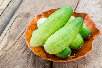 Fresh cucumber in wooden plate on wooden table