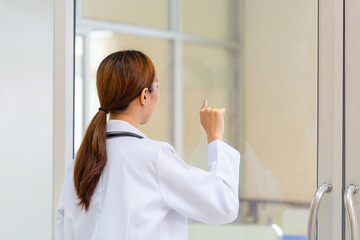 Back view of Young female doctor knocking on door