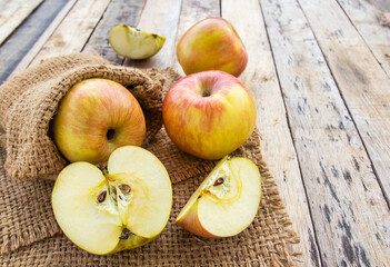 Naklejka na ściany i meble Fresh apples in burlap sack on wooden table background